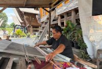 Suasana Desa Tenganan Pegringsingan yang khas dengan tata letak rumah tradisionalnya, mencerminkan kehidupan masyarakat Bali Aga yang teguh menjaga warisan leluhur mereka. Para perempuan Bali Aga tampak tengah menenun kain gringsing, sebuah warisan budaya tak ternilai yang membutuhkan kesabaran dan keahlian tinggi.