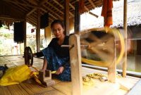 Pemandangan rumah-rumah tradisional dengan tembok batu tinggi di Desa Tenganan Pegringsingan, menunjukkan arsitektur unik yang dijaga ketat oleh masyarakat Bali Aga. Seorang wanita Bali Aga sedang menenun kain gringsing menggunakan teknik double ikat, sebuah warisan budaya tak ternilai yang membutuhkan kesabaran dan keahlian tinggi.